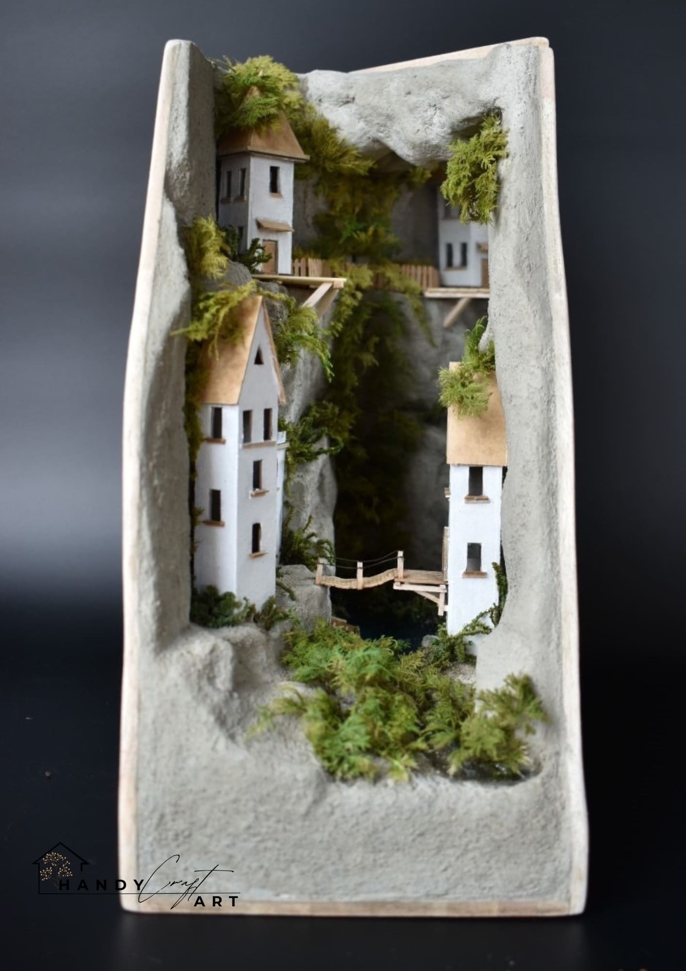Artistic book nook with a village scene with houses and greenery on a textured surface.
