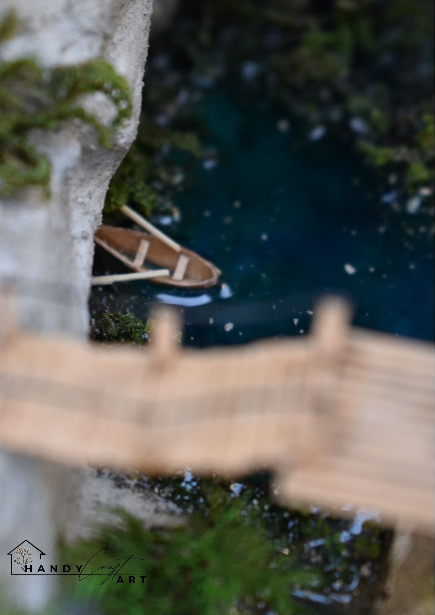Small wooden boat on a pond in the handmade  booknook by HandiCraftArt.