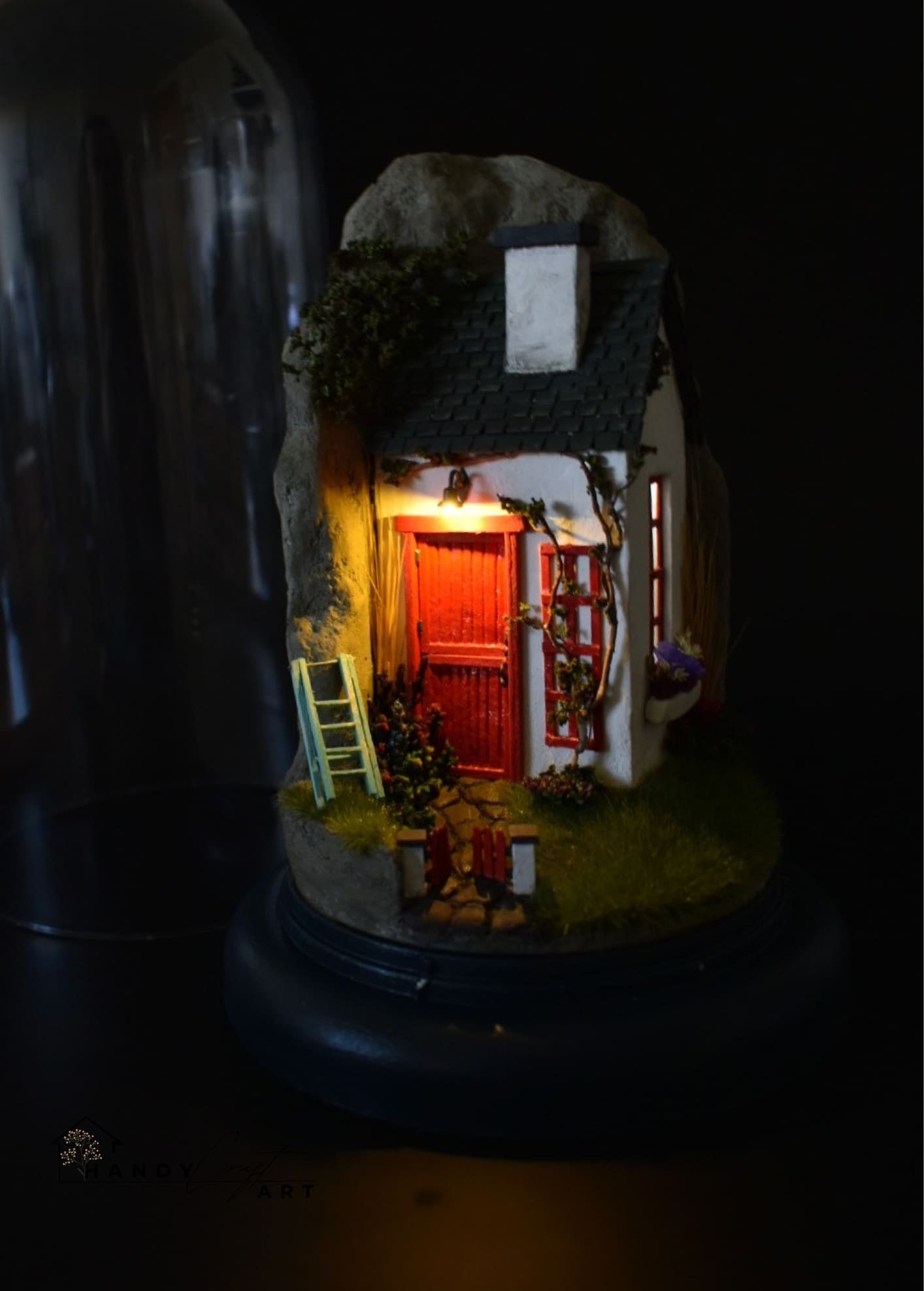 Diorama small model of Irish house with a red door and lit interior, set against a dark background